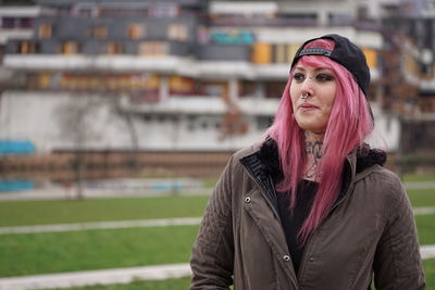 Smiling woman with pink hair standing at lawn in city