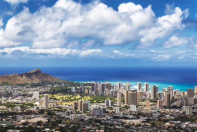 Aerial view of buildings by sea against sky