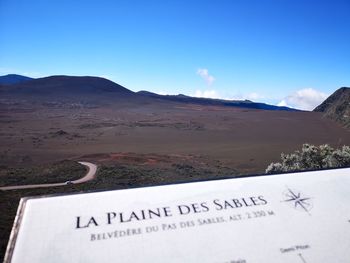 Information sign on landscape against blue sky