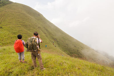 Rear view of men walking on landscape against sky