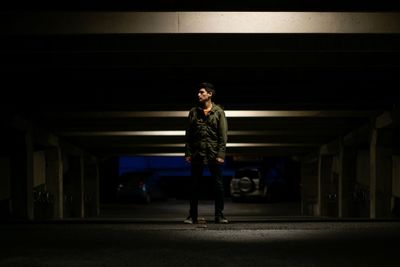 Full length of young man standing in parking lot at night