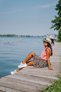 Woman sitting on shore against sky