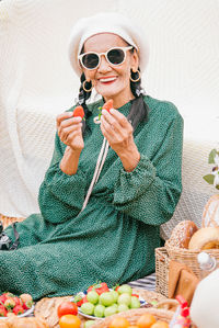 Young woman wearing sunglasses holding strawberry outdoors