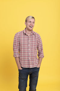 Portrait of smiling man standing against yellow background