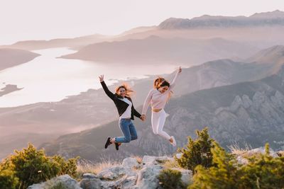 Woman jumping in mountains against sky