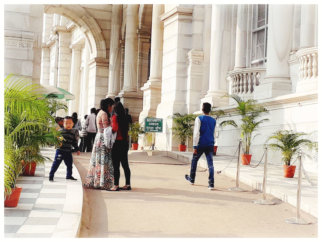 REAR VIEW OF PEOPLE WALKING ON COLONNADE