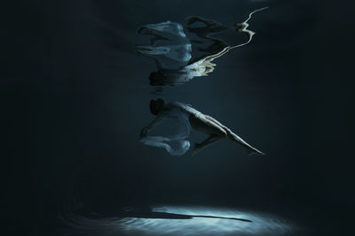 Young woman with reflection swimming undersea