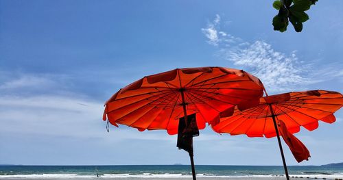 Red umbrella on beach against sky