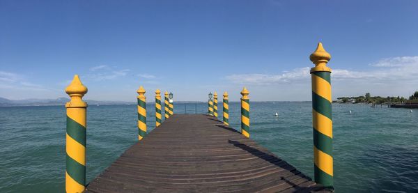 Pier amidst sea against blue sky