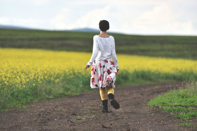 Rear view of woman walking on field