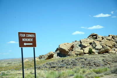 Road sign by mountains against blue sky