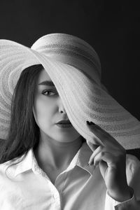 Portrait of woman wearing hat against black background