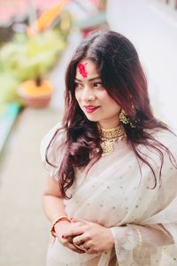 Smiling beautiful woman looking away while wearing sari and jewelries outdoors