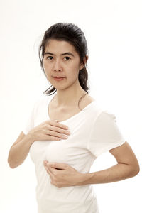 Portrait of woman with hands on chest standing against white background