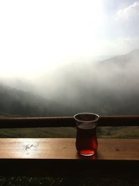 Coffee on table by mountains against sky