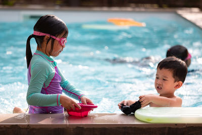 Siblings enjoying at swimming pool