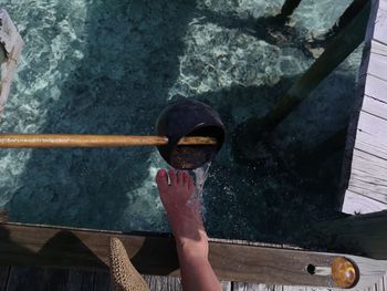 Low section of woman washing foot on pier over sea