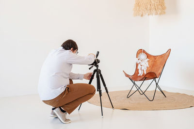 Rear view of woman sitting on chair against white background