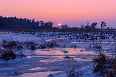 Scenic view of snow covered landscape against sky at sunset