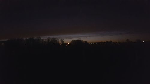 Silhouette trees against sky at night