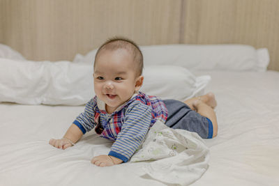 Cute baby girl lying on bed at home