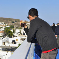 Rear view of man standing against sky in city