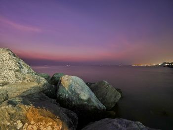 Rocks by sea against sky during sunset