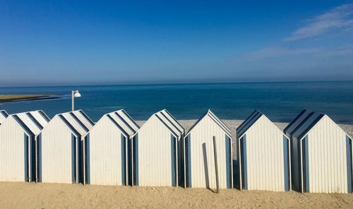 Beach huts in row against blue sky 