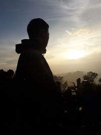 Silhouette people standing by mountain against sky during sunset