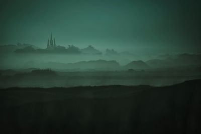 Silhouette of mosque against sky during foggy weather
