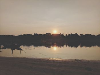 Silhouette of birds in lake during sunset