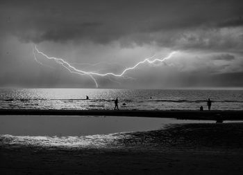 Beach at coast of north sea illuminated by lightning, black and white photography