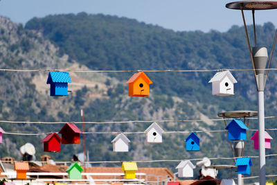 Bird houses hanging from rope by street light against mountain