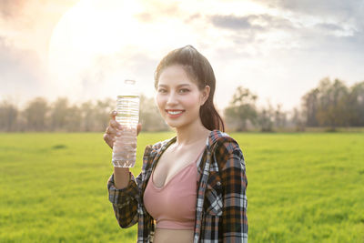 Portrait of smiling young woman standing on field