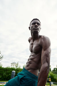 Low angle view of shirtless man standing against sky