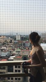 Young woman looking at cityscape through window