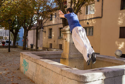 Full length of man jumping in artificial pond