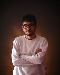 Portrait of young man standing against black background