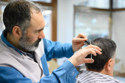 Hairdresser cutting customer hair