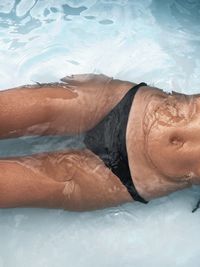 Low section of man relaxing in swimming pool