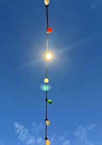 Low angle view of illuminated street light against blue sky. be different even without shining