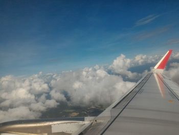 Airplane flying over clouds against blue sky