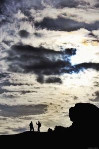 Silhouette of people against cloudy sky