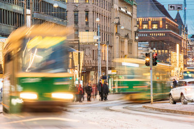 Blurred motion of tramway on road against building in city during winter