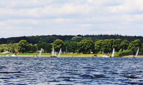 Boat sailing in river against cloudy sky