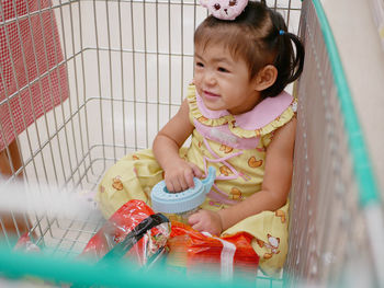 High angle view of cute girl sitting in shopping cart