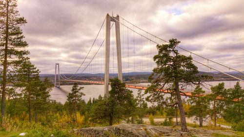 Bridge over river against cloudy sky