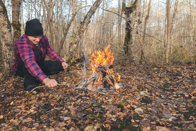 Man roasting food in campfire at forest