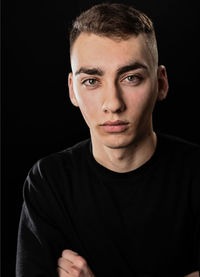 Portrait of young man against black background