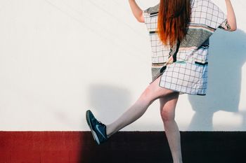 LOW SECTION OF WOMAN STANDING ON FLOOR AGAINST WALL